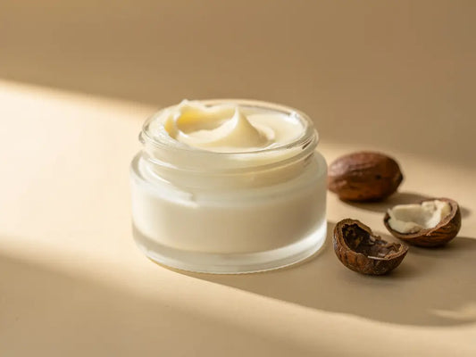 Raw unrefined shea butter in a wooden bowl surrounded by nuts.