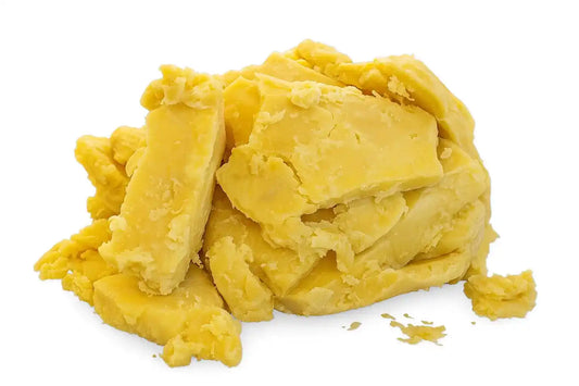 Raw yellow shea butter 1 lb on wooden surface with green leaves, showcasing its smooth texture